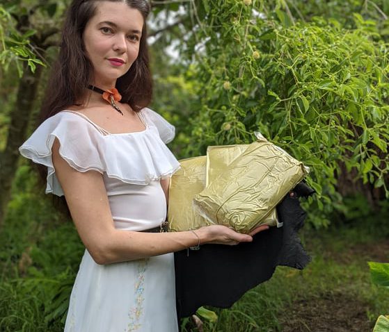 Jamie holding kratom powder in front of kratom tree