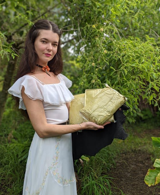 Jamie holding kratom powder in front of kratom tree